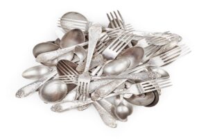 Pile of aged vintage silver cutlery (forks, spoons, knifes) isolated on white background
